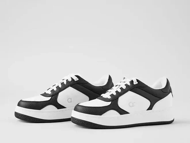 Czarno-białe sneakersy na grubej podeszwie na jasnym tle.